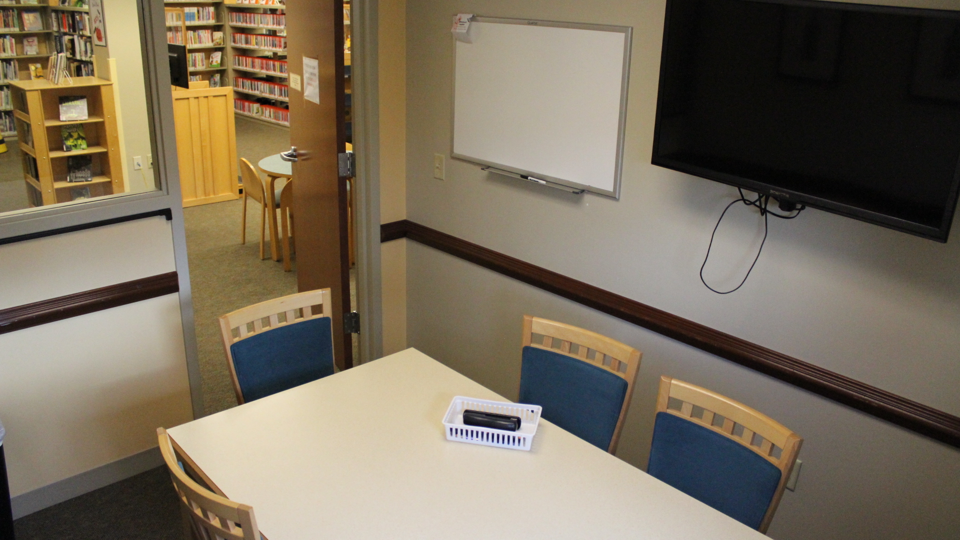 Study room B, with table and chairs, wall-mounted television, and dry-erase whiteboard