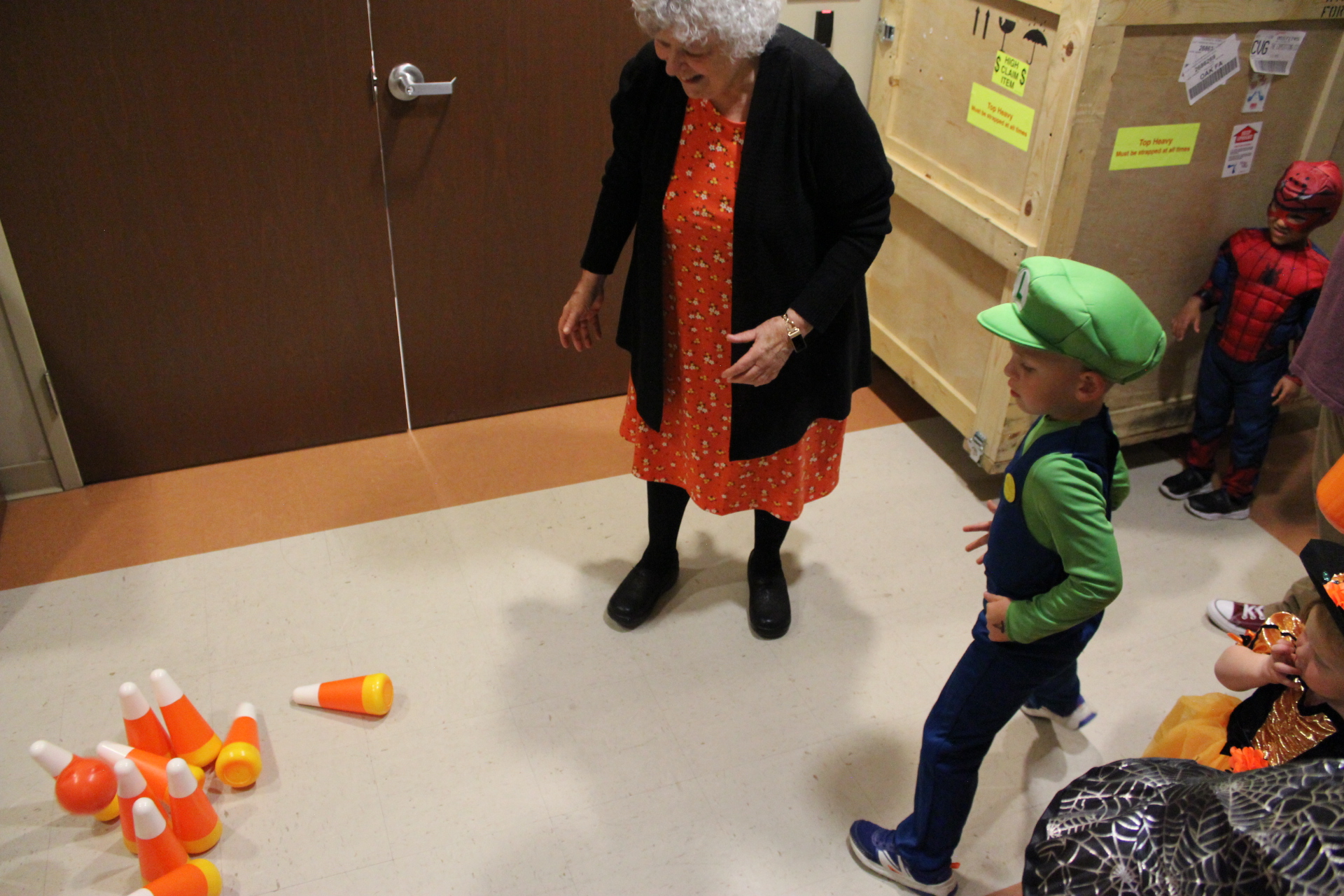 Friend of the Library Lois cheering while child dressed as Luigi plays candy-themed bowling game