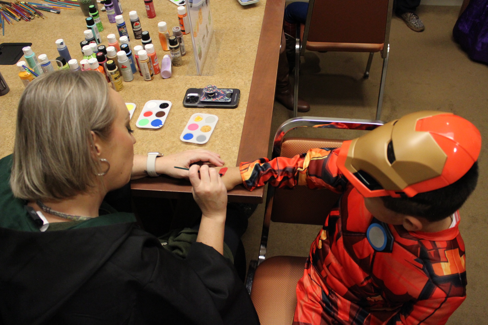 Library Executive Director Jasmyne painting costumed child's hand