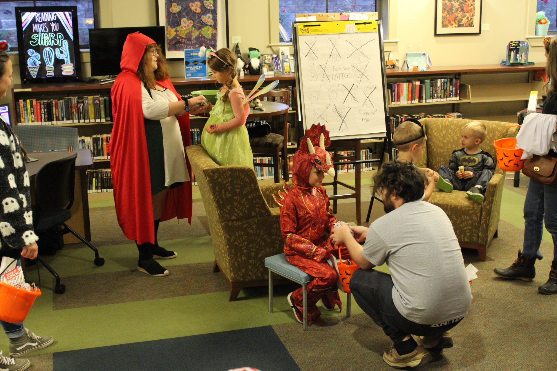 Teen Librarian Megan and Library Programming Assistant Ronnie applying temporary tattoo to costumed children