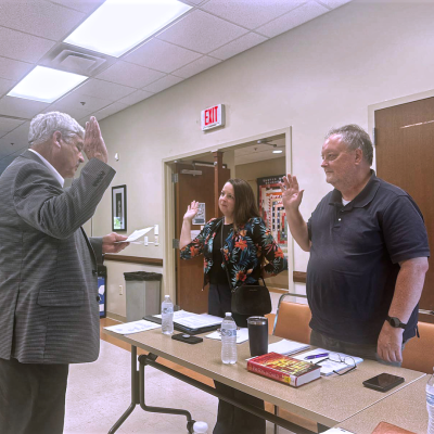 Rowan County Judge-Executive Harry Clark administering the oath of office to new board members Doctor Shana Savard-Hogge and Drew Henderson