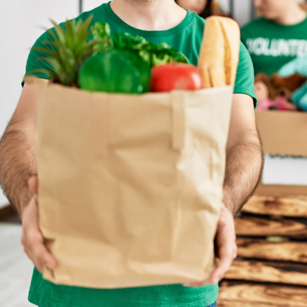 Unidentified volunteer offering paper bag of groceries