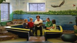 Miss Sandy reading to children in the library's kids' area.