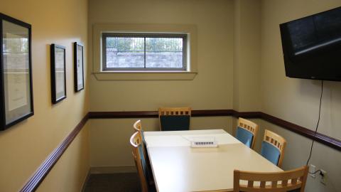 Study room A, with table and chairs, wall-mounted television, window, and artwork