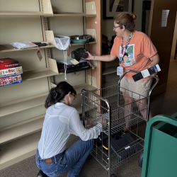 2 librarians stocking shelves with new items